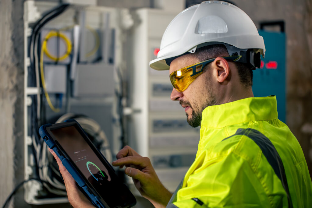 Técnico con casco y gafas de seguridad utiliza tableta digital para gestionar datos en Vaca Muerta.