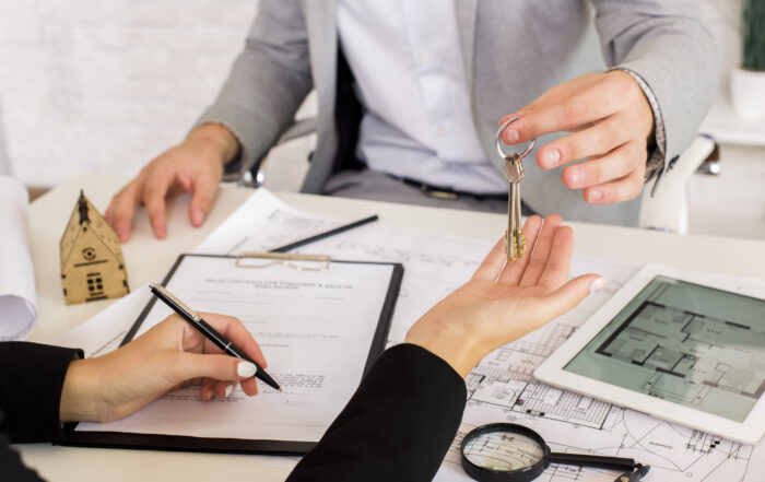 Agente entregando llaves durante firma de contrato de inversión inmobiliaria en Miami