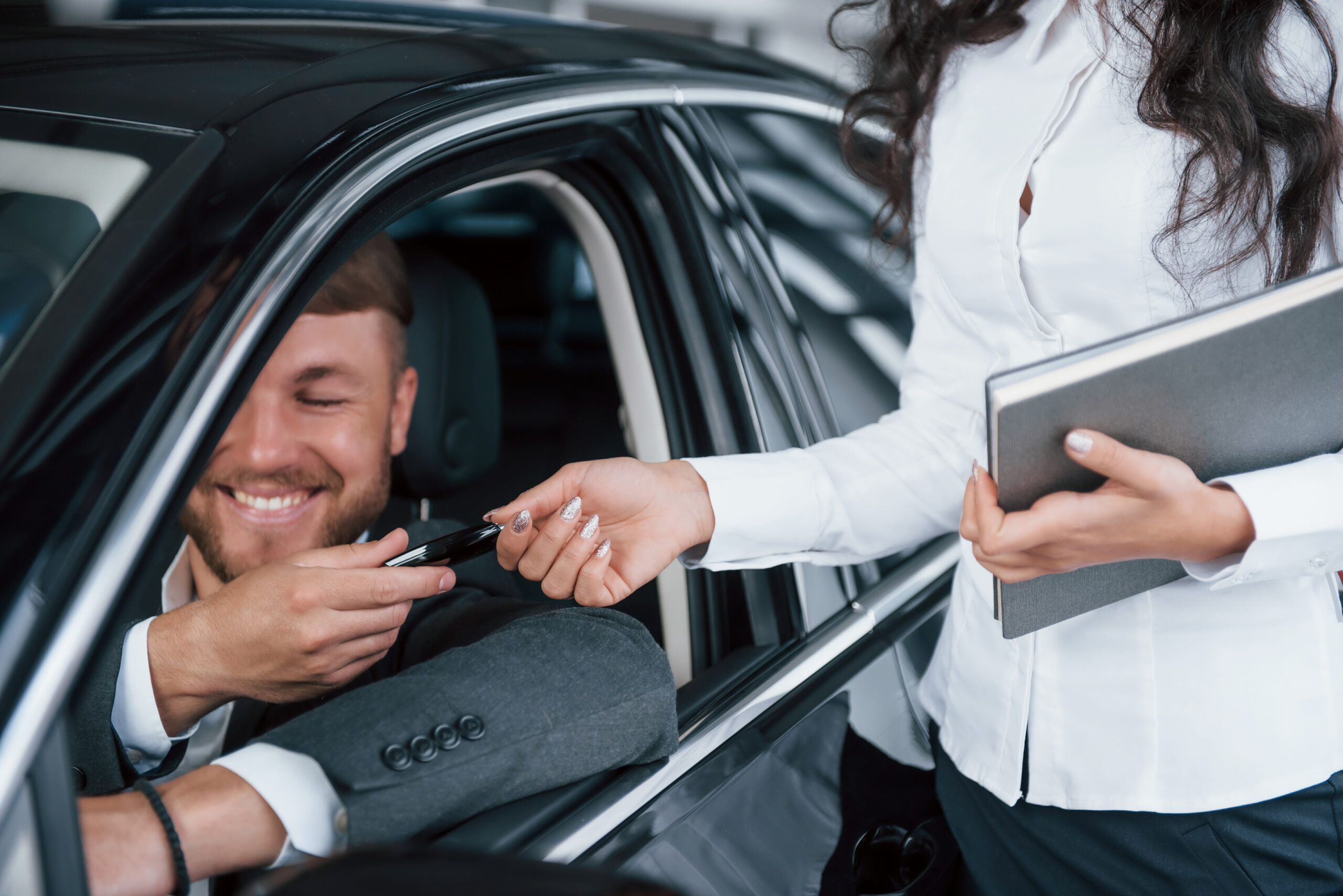 Cliente recibiendo las llaves de su auto nuevo de una gerente en concesionaria, simbolizando una compra exitosa.