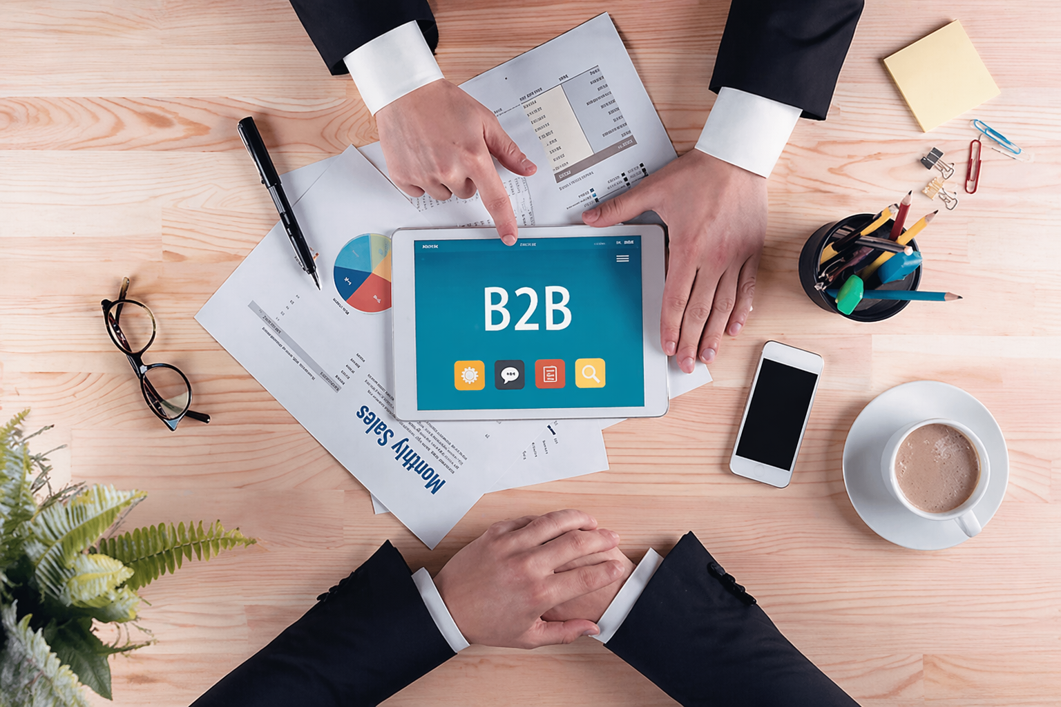 Vista cenital de equipo de trabajo analizando contenido B2B en una tablet sobre una mesa con documentos y gráficos, representando la nutrición de leads en entornos empresariales.